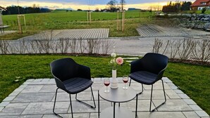 An outdoor seating area with two black chairs and a small round table, surrounded by a stone patio. - HochgratBlick.modern.cozy.relaxed (Argenbühl)
