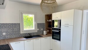 Una cocina moderna con armarios blancos, un lavamanos negro y un horno empotrado.