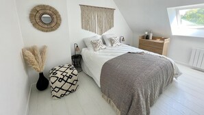 Un dormitorio moderno con cama, mesita de noche, lámpara, adornos en la pared y una ventana.