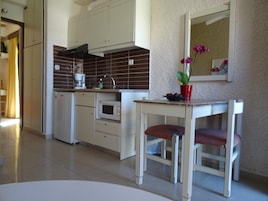 A compact kitchen with white cabinets, a microwave, and a small dining table with a chair.