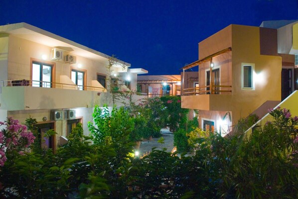 A multi-story building with balconies, air conditioning units, and a courtyard with potted plants and flowers. - Lito Apartments (Kantanos-Selino)