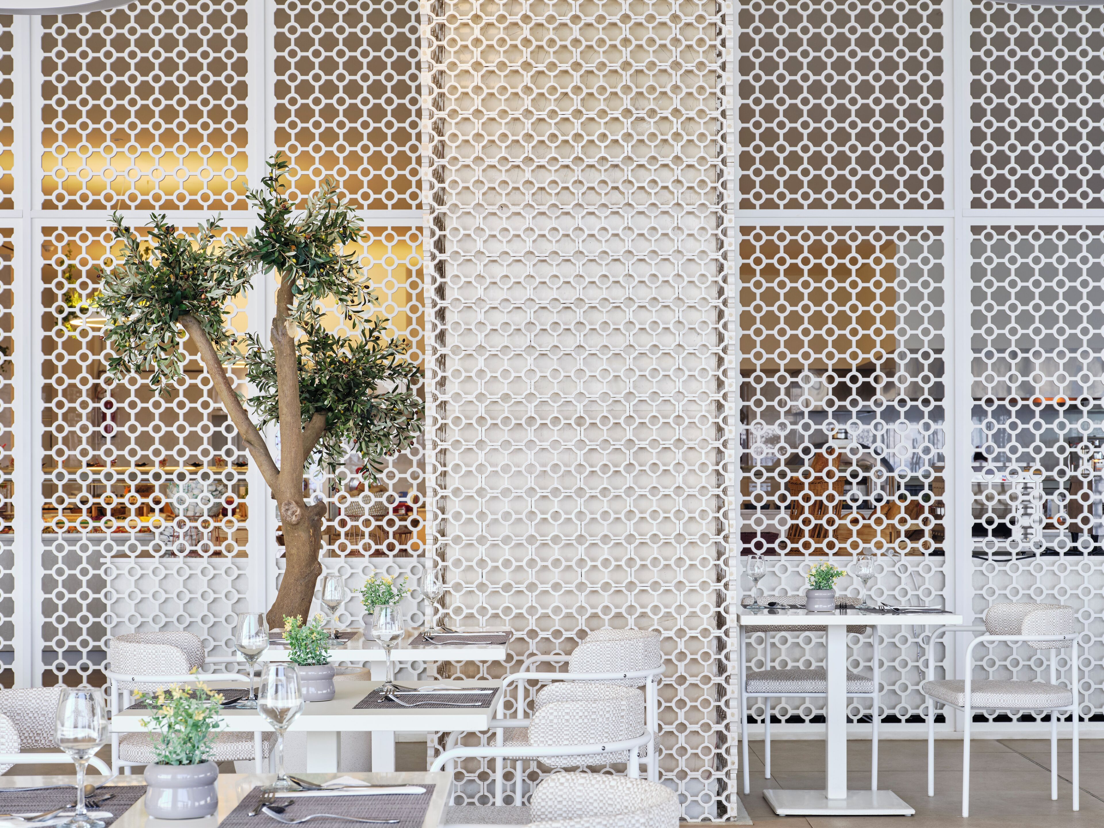 Ein Restaurant mit weißen Möbeln und einem dekorativen weißen Gitter.