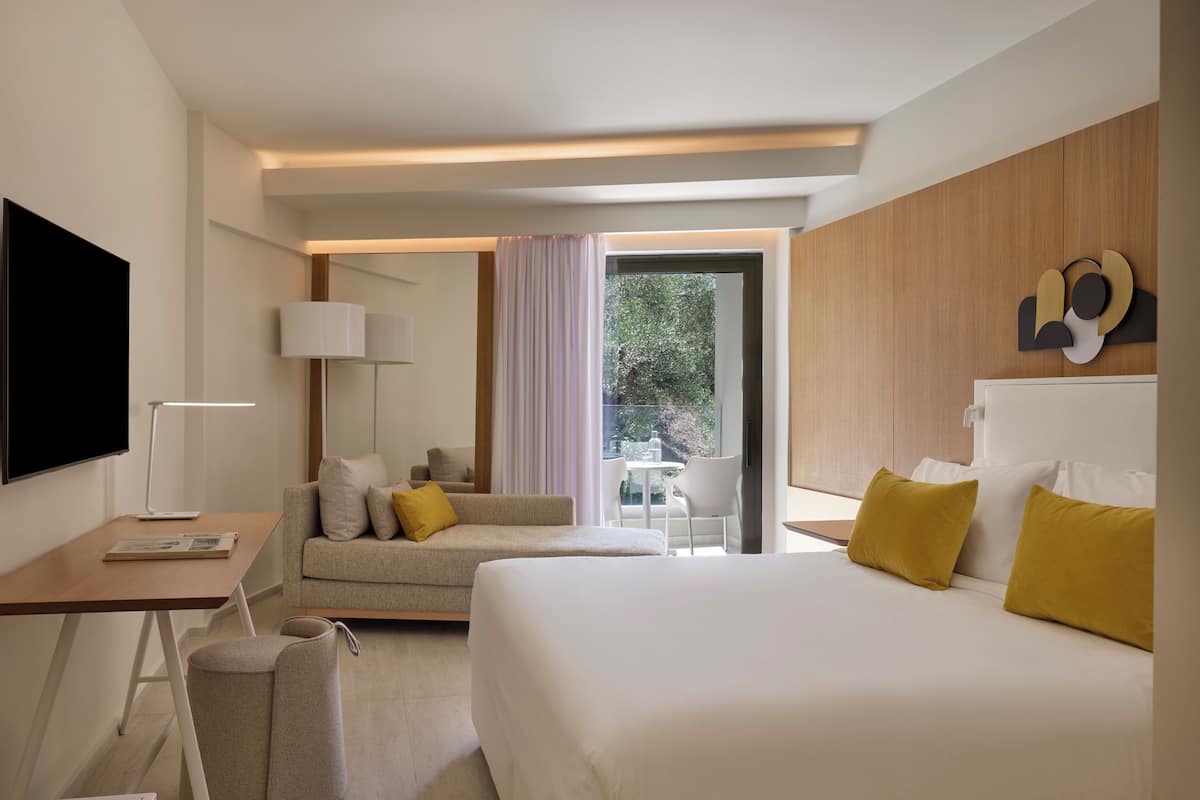 Une chambre d’hôtel moderne avec un grand lit, un canapé, un bureau avec une lampe et un téléviseur.