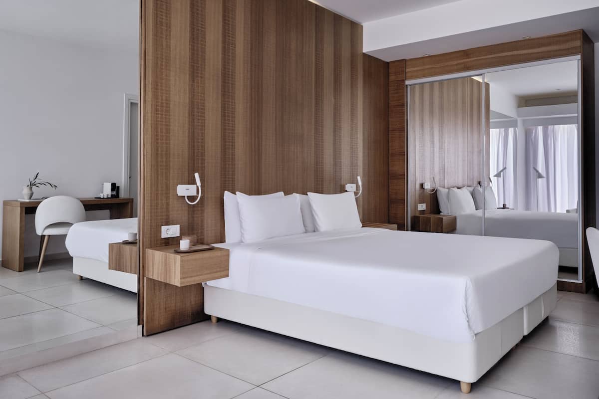 Une chambre d’hôtel moderne dotée d’un grand lit, d’un mur décoratif en bois, d’un bureau avec une chaise et d’un miroir.