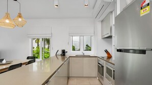 Una cocina moderna con una isla central, electrodomésticos de acero inoxidable e iluminación colgante.