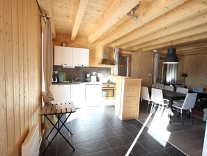 A wooden interior with a kitchen, dining area, and a small table with chairs. - Semi-detached chalet on 3 levels, up to 8 people, pets allowed (Chamrousse)
