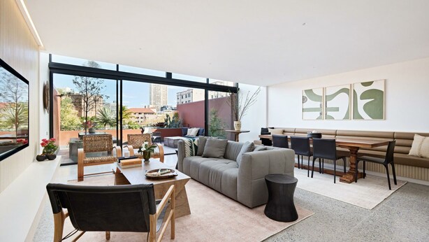 A modern living room with a large window, a sofa, a dining table, and a coffee table. - Fox on Macleay is a Two Bedroom Apartment (Elizabeth Bay)