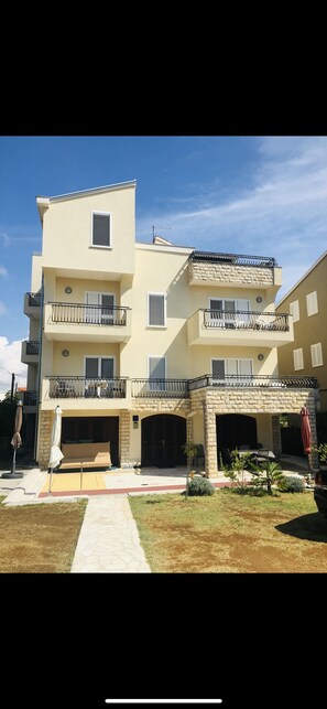 A two-story building with balconies, a covered outdoor seating area, and a paved driveway.