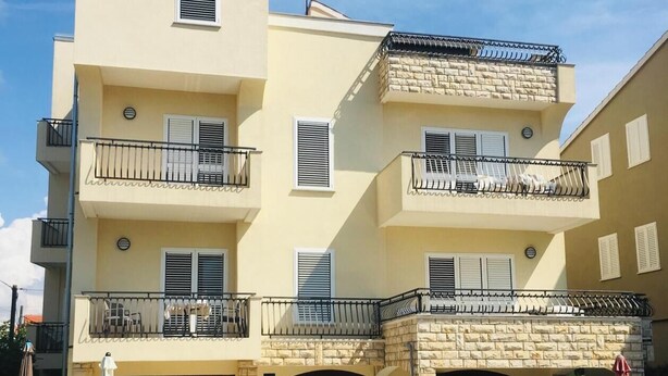 A multi-story residential building with balconies, a stone facade, and a small courtyard with outdoor seating. - Großzügige Ferienwohnung - 2 Min. vom Strand Entfernt (Vodice)