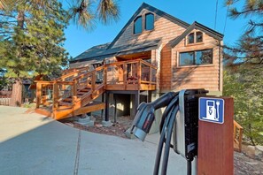 A wooden cabin with a covered outdoor area, a staircase, and an EV charging station. - Aspen Escape by Destination Big Bear: Incredible Views and Game Table. Close to Bear Mountain and the Zoo! EV Charger! (Big Bear Lake CA)