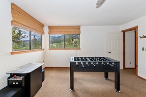 A room with a foosball table, a foosball table on a stand, and a door. - Aspen Escape by Destination Big Bear: Incredible Views and Game Table. Close to Bear Mountain and the Zoo! EV Charger! (Big Bear Lake CA)