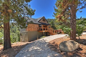 Eine Holzhütte mit einer Holzterrasse und einer Treppe, die zu einer Veranda führt, unter blauem Himmel.