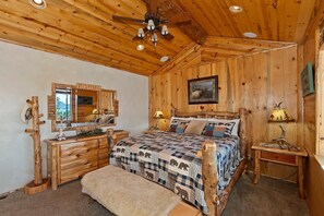 A wooden cabin bedroom with a bed, dresser, and a ceiling fan. - Eagle View Lodge by Destination Big Bear: Beautiful Custom-Built Luxury Lakeview Cabin Located in Castle Glen Estates! Spa!Pool Table! Air Conditioning Throughout Home! (Big Bear Lake)