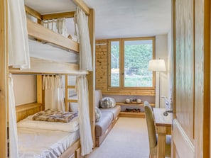 Quarto com beliche, escrivaninha e janela.