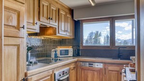 A kitchen with wooden cabinets, a microwave, an oven, and a dishwasher. - Charming 2-bedroom apartment with fireplace and parking in Megève (Megève)