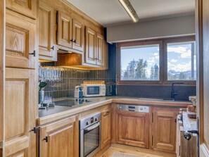 A kitchen with wooden cabinets, a microwave, an oven, and a dishwasher.