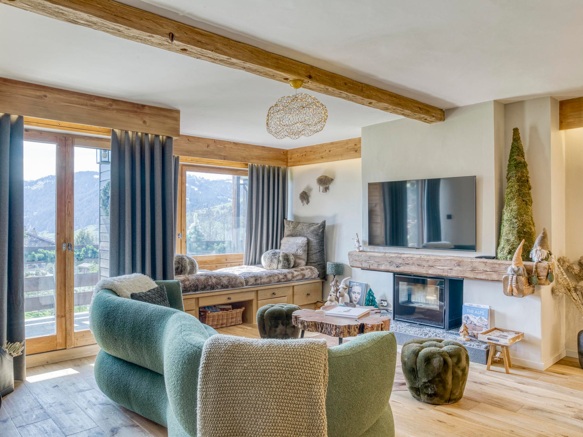 A cozy living room with a fireplace, comfortable seating, and a large window offering a scenic view.