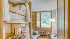A cozy room with bunk beds, a desk, and a window with a view of greenery. - Charming 2-bedroom apartment with fireplace and parking in Megève (Megève)