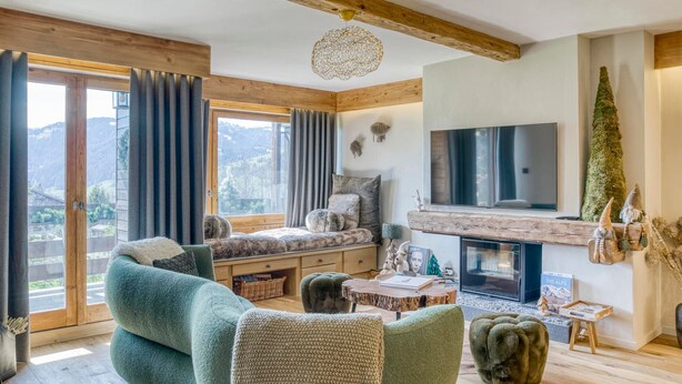 A cozy living room with a fireplace, comfortable seating, and a large window offering a scenic view. - Charming 2-bedroom apartment with fireplace and parking in Megève (Megève)
