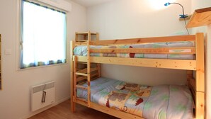 Dormitorio con literas, ventana, radiador y lámpara de escritorio.