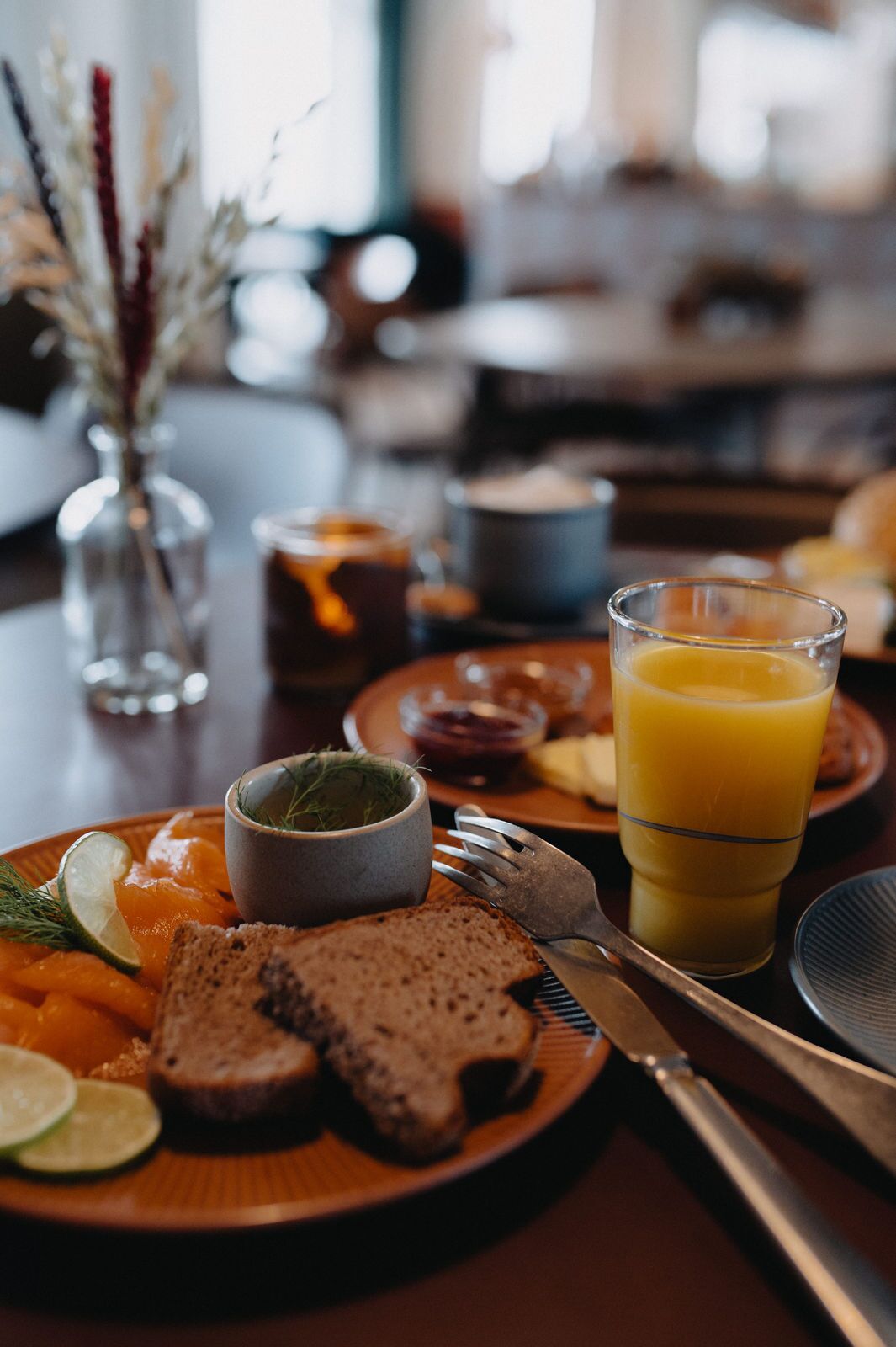 A breakfast setting with a plate of salmon, bread, and a glass of orange juice.