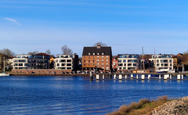 A waterfront building with multiple floors, a flat roof, and a visible entrance.