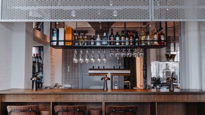A bar area with a wooden counter, bar stools, and a variety of bottles and glasses on shelves. - Südspeicher (Kappeln)