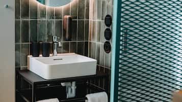 A modern bathroom with a round mirror, a white sink, and a towel rack.