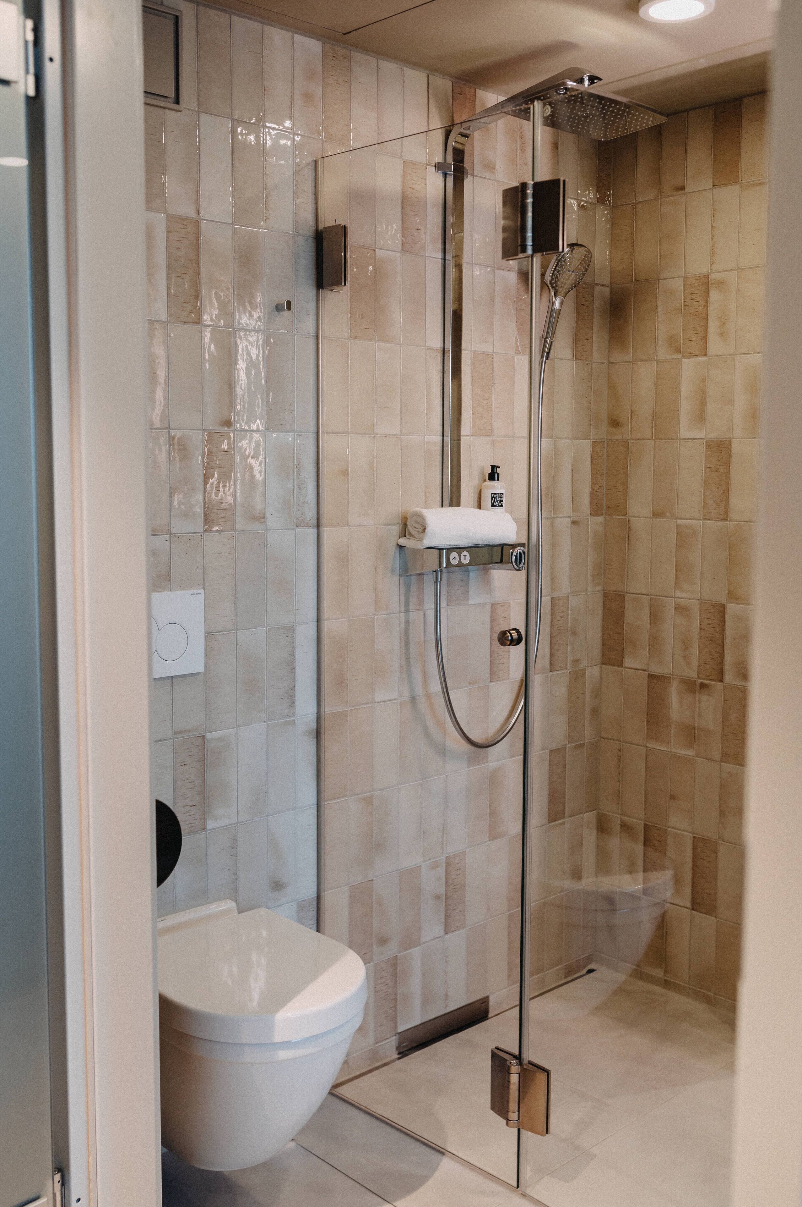 Et moderne badeværelse med brusekabine i glas, toilet og håndvask.