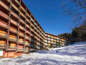 A multi-story hotel with balconies, set against a snowy landscape.