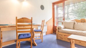 Una habitación acogedora con una mesa de madera, dos sillas, un sofá y una ventana con vistas a árboles.