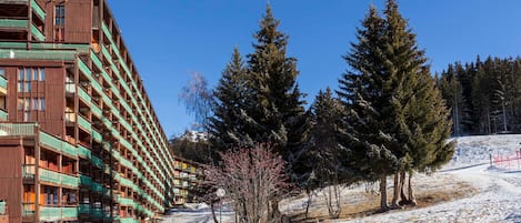 A multi-story hotel with balconies, surrounded by snow-covered ground and evergreen trees.