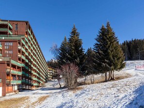 A multi-story hotel with balconies, surrounded by snow-covered ground and evergreen trees.