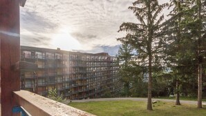 Un balcón con vistas a un edificio de varios pisos y un árbol grande.