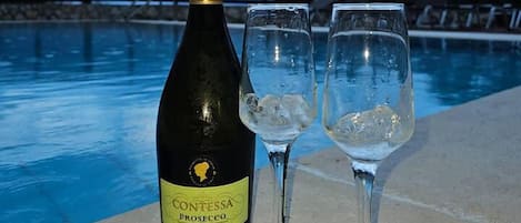 A bottle of Contessa Prosecco Extra Dry and two glasses of wine by a poolside.