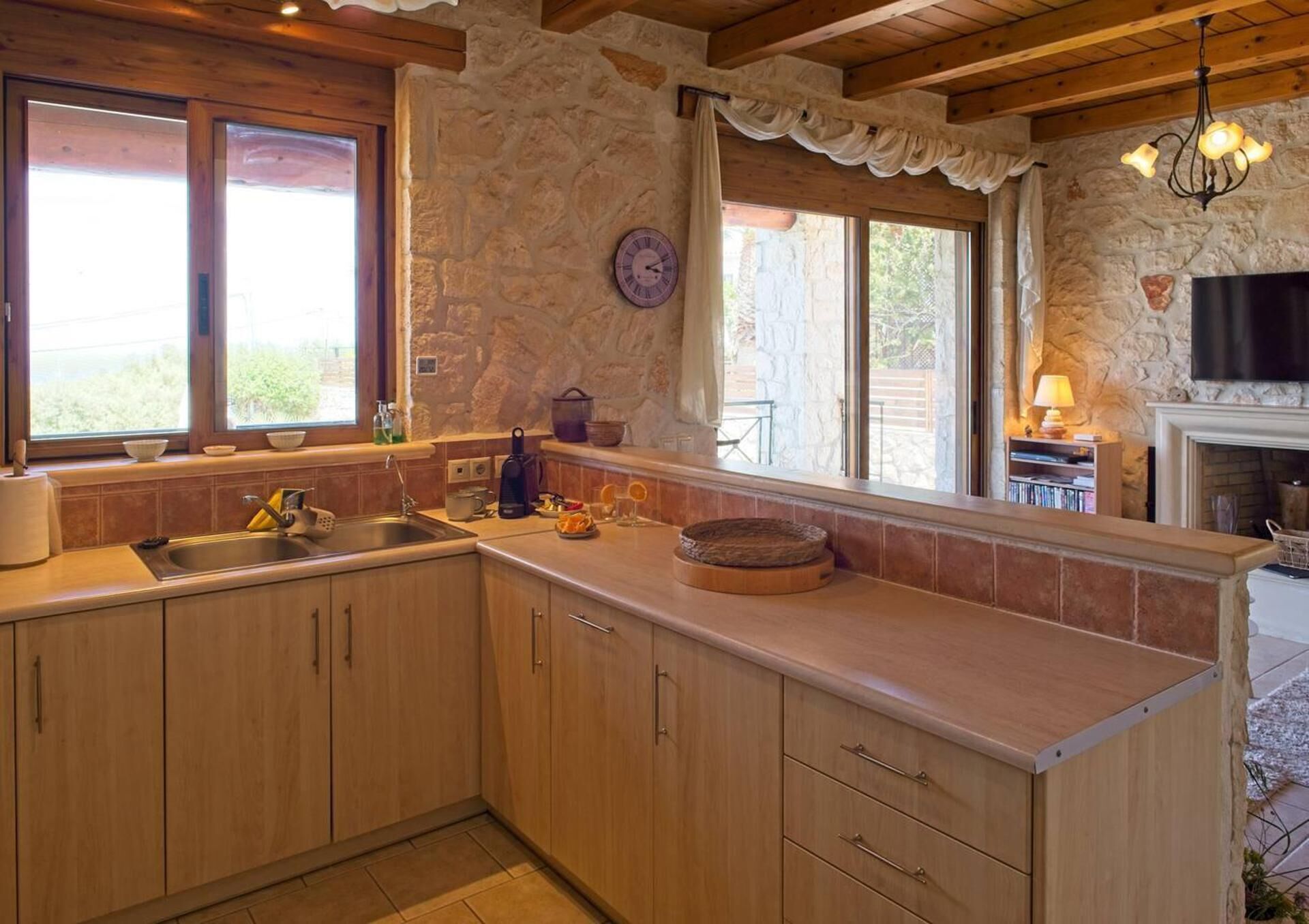 Eine Küche mit Holzausstattung, einer Steinwand, einer integrierten Kochinsel und einem Kamin.
