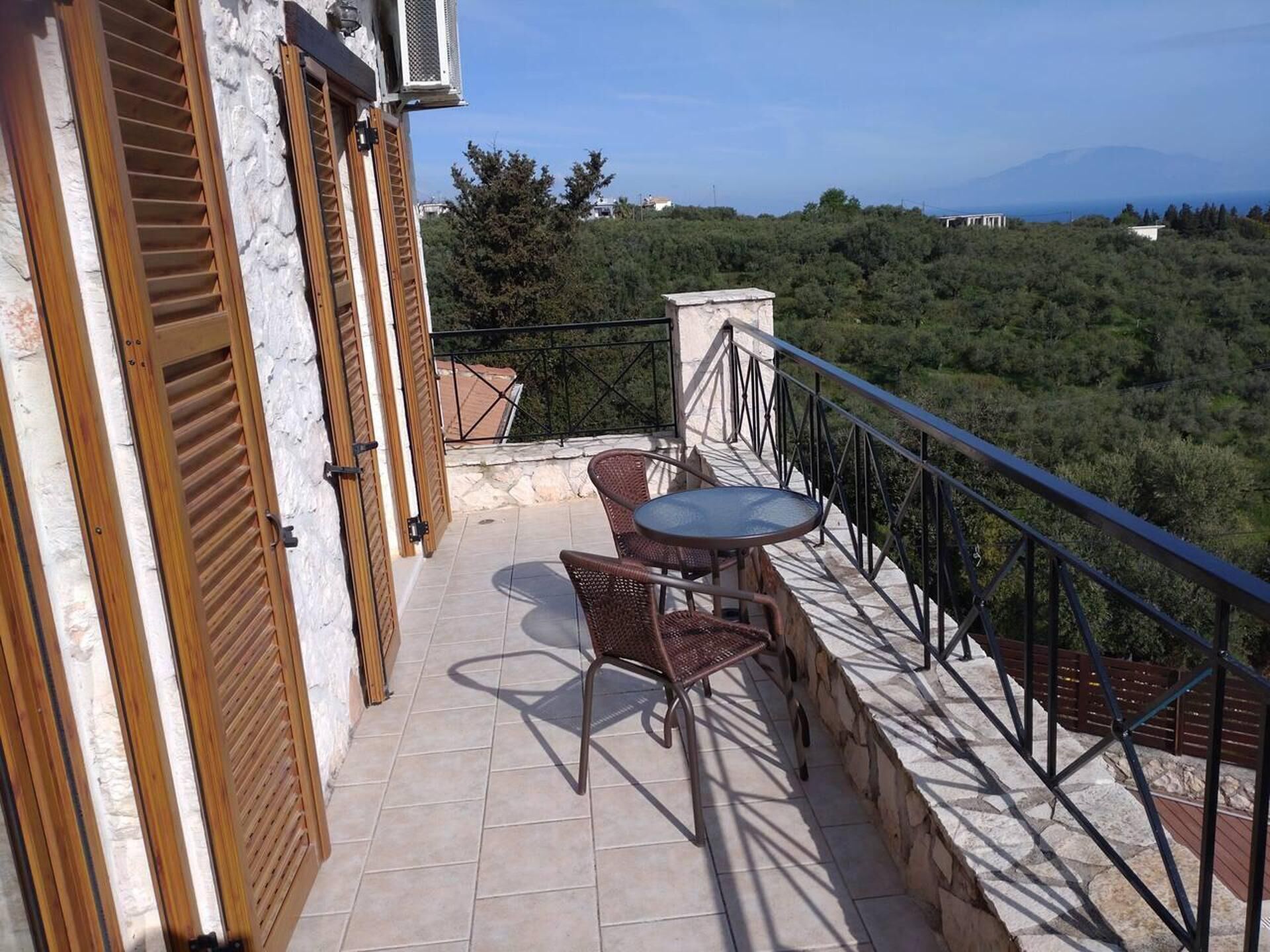 Ein Balkon mit Tisch und Stühlen mit Blick auf eine gebirgige Landschaft.