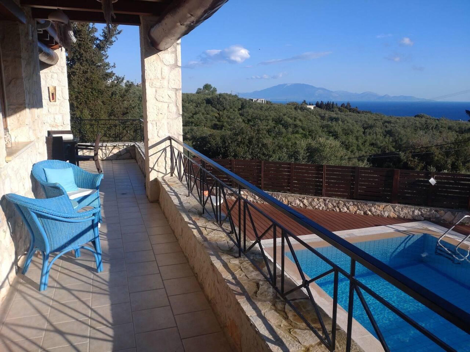 A pool area with a view of the sea and hills.