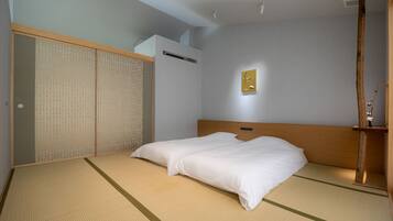 A traditional Japanese-style room with tatami flooring, a low wooden bed, and a shoji screen door.