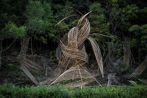 Une sculpture complexe, réalisée à partir de tiges de bambou entrelacées, et placée dans un environnement naturel.