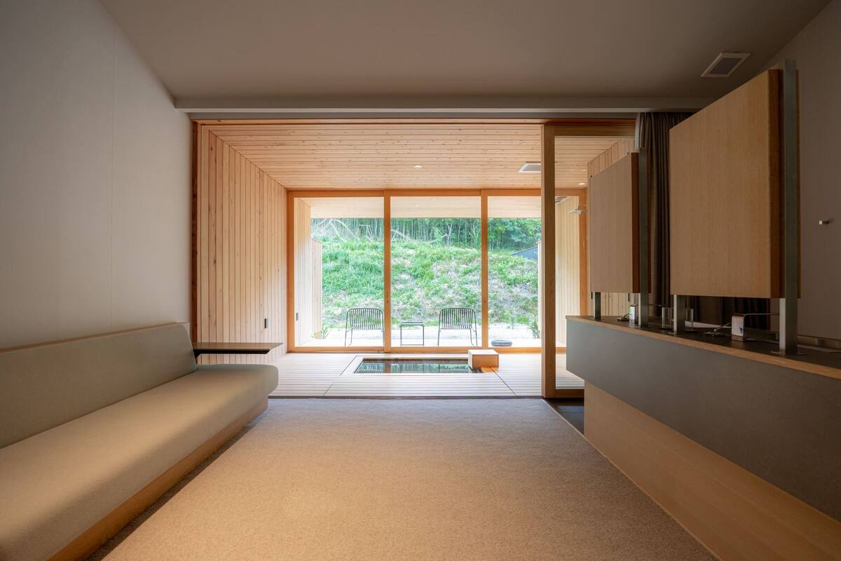 A minimalist room with a sliding glass door leading to an outdoor garden area.