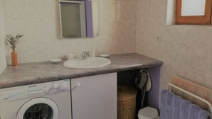 A compact bathroom with a washing machine, a sink, and a mirror. - Charming Detached Cottage with Large Garden, Near Forest and Karting (La Celette)