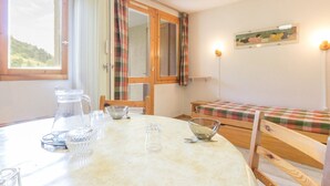 A cozy room with a round table, a bed with plaid bedding, and a painting on the wall.