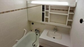 A bathroom with a bathtub, a sink, and a mirror.