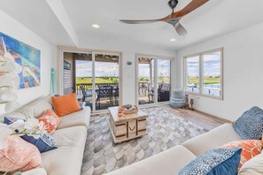 Bright coastal living room with floor-to-ceiling water views. - Bayfront Beauty - Stylish Bay Front Escape with Fire Pit (Avalon)