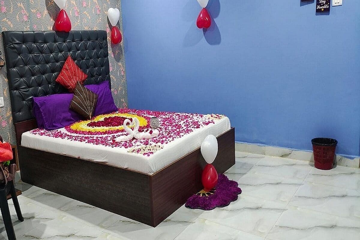 Una cama con un diseño de cisne, globos rojos y blancos, y una almohada morada.