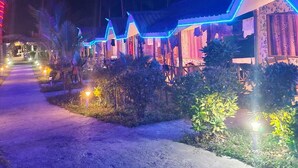 A row of bungalow-style accommodations with a pathway leading to them, surrounded by greenery. - Honey Moon Beach Resort (Port Blair)