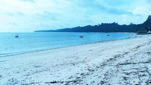 A beach with a sandy shore and calm water. - Honey Moon Beach Resort (Port Blair)
