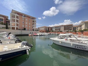 A marina with several boats docked, surrounded by multi-story buildings with balconies. - Studio 2 people with pool in Fréjus (Fréjus)