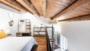A bedroom with a wooden ceiling, a bed, a ladder, a small table, and a mirror. - Modern and Spacious Apartment in Noto, Sicily (Noto)